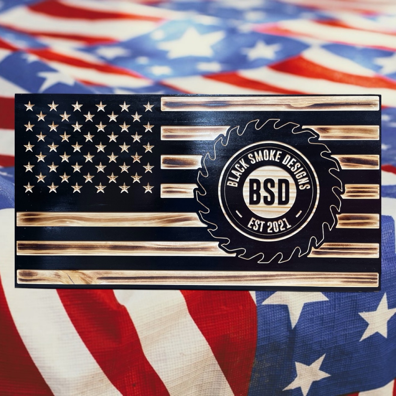 CNC-carved wooden American flag with the Black Smoke Designs saw-blade logo